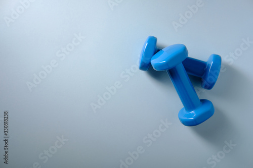 Two blue dumbbells on a blue background, a place for an inscription