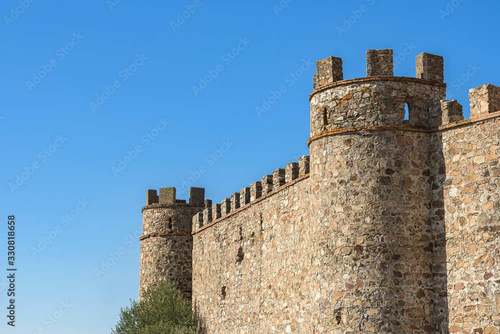 Side of the Alconchel castle, with its elegant battlements, in the southwest of Spain