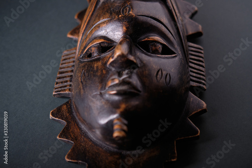 Ancient wooden african mask on a dark background, side view © grek881