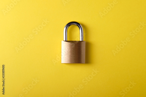 Small metal padlock on a yellow background
