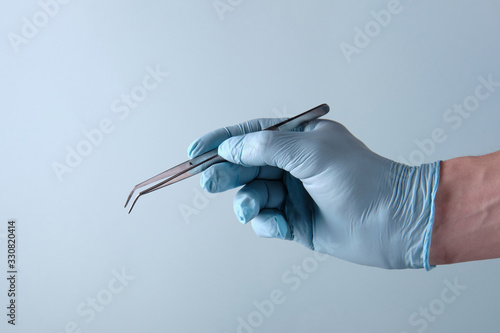 Dentist holds tweezers on a blue background