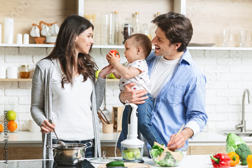 Cheerful parents preparing lunch with baby son at kitchen photo