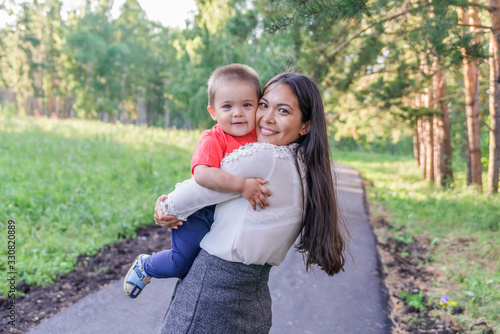 A happy young mother plays and has fun with her young son in nature, in the Park. The mother is talking to the baby. The concept of a happy family, motherhood. A mother's walk with a small child. Moth