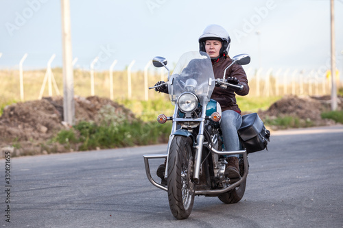 Fototapeta Naklejka Na Ścianę i Meble -  Woman motorcyclist riding on her chopper motorcycle on road