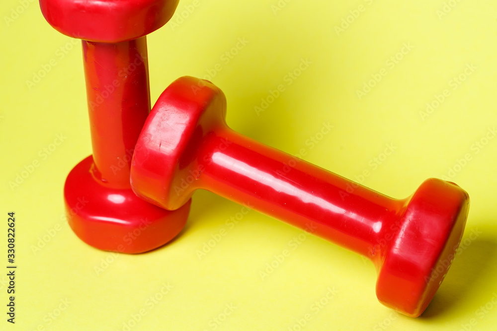 red sports dumbbells on a yellow background red sports dumbbells on a yellow background