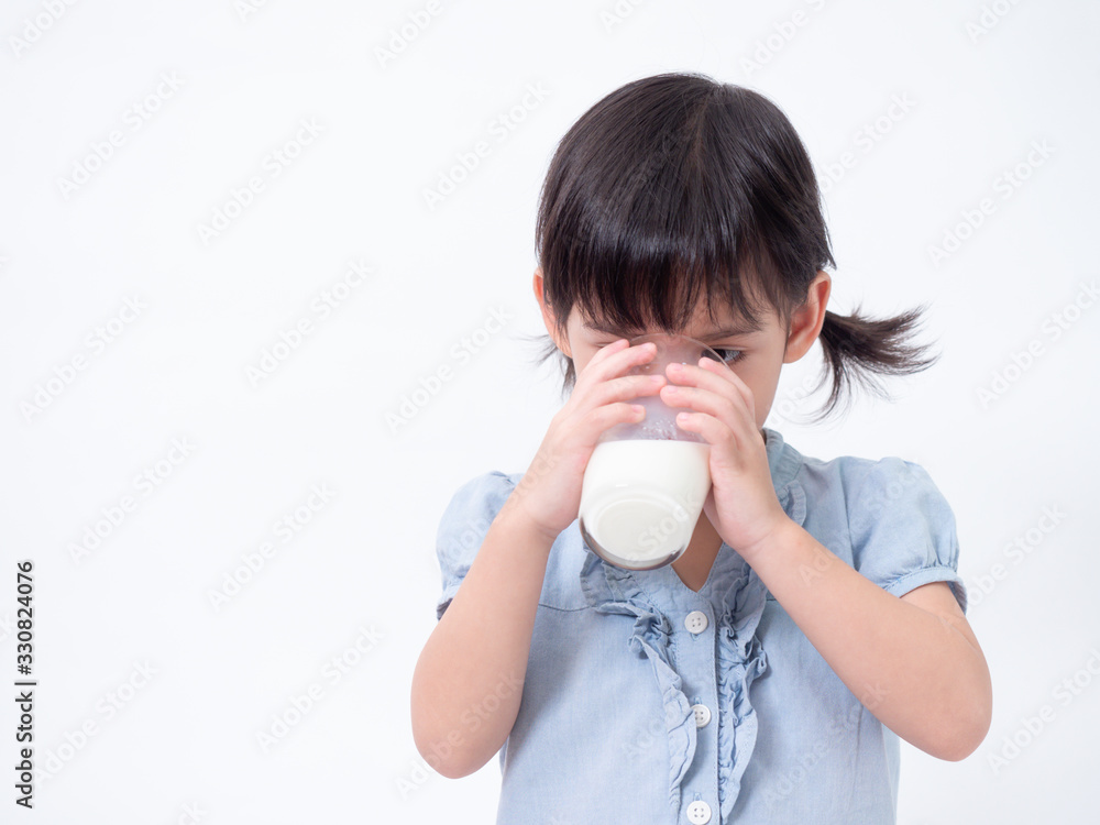 Asian little cute girl 4 years old holding and drinking milk from glasses over white background. Milks is essential and nutrition for the child's body. Asian little cute girl 4 years old holding and drinking milk from glasses over white background. Milks is essential and nutrition for the child's body.