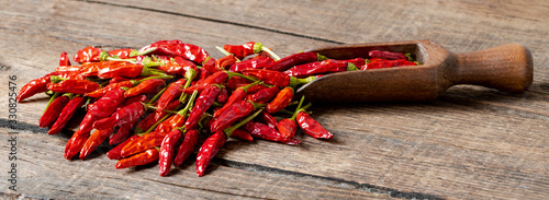 Schilderij op canvas Close-up of dried red cayenne chillies and a wooden spoon on an old wooden table