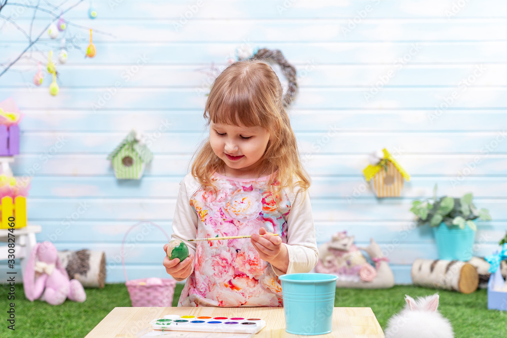 Happy Easter! A cute little girl paints an Easter egg with a brush. Happy Easter! A cute little girl paints an Easter egg with a brush.