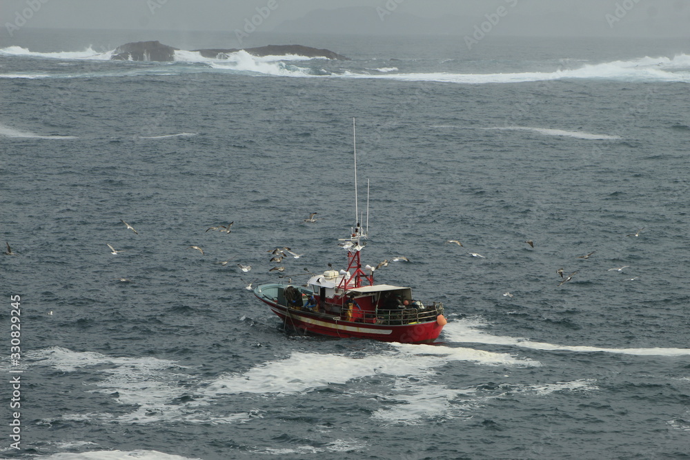 Fototapeta premium Small fishing boat, fishing near the coast, in bad weather, in La Coruña, Spain