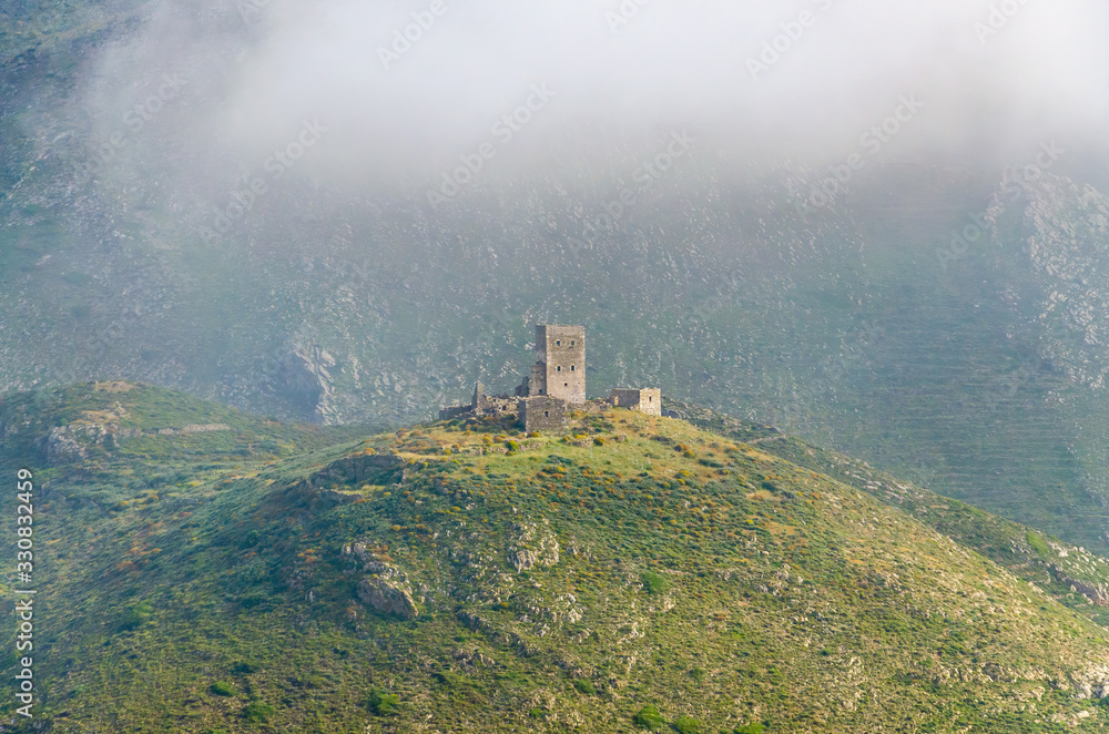 The remnants of an old stone built tower in the fog in Mani Laconia Greece