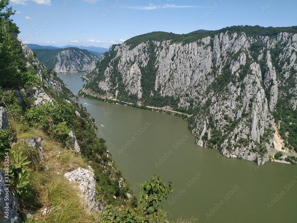 Girl standing on a rocky cliff hundred meters above the Danube Valley between Romania and Serbia, Yoga posing in the sun, meditating with arms wide open Girl standing on a rocky cliff hundred meters above the Danube Valley between Romania and Serbia, Yoga posing in the sun, meditating with arms wide open