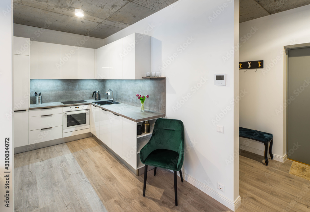 Modern interior of kitchen in private house. Clean white kitchen set. Flowers. Green chair. Modern interior of kitchen in private house. Clean white kitchen set. Flowers. Green chair.