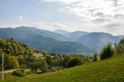 Landscape view on the beautiful hill with houses and trees in morning mountains near the Kvasy village . Summer vacation in countryside. Atmospheric rustic moment. 