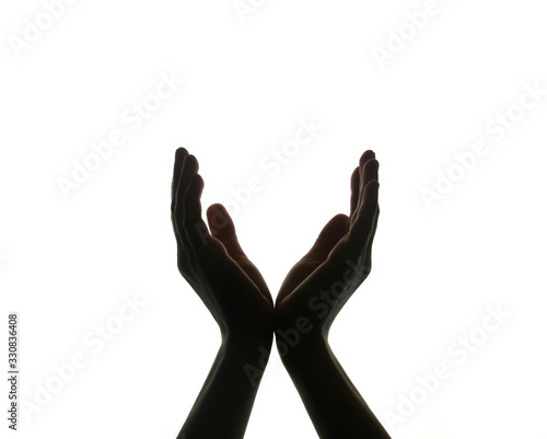 the two hands are joined, and the palms of the hands are open, as if holding something. dark hands silhouetted against a white background. the palms form the letter V. hands hold the ball.