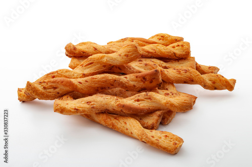 Cheesy flavor cracker, salty treat and food rich in carbohydrates group of many twisted golden cheese sticks isolated on white background