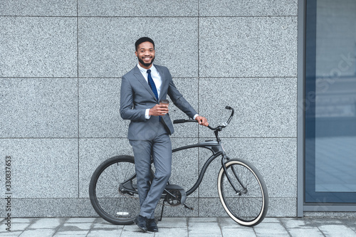 Handsome afro businessman holding coffee and bike