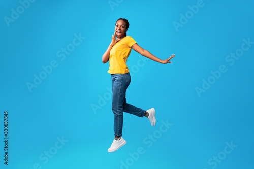 Cheerful Woman Shouting Jumping In Air On Blue Background