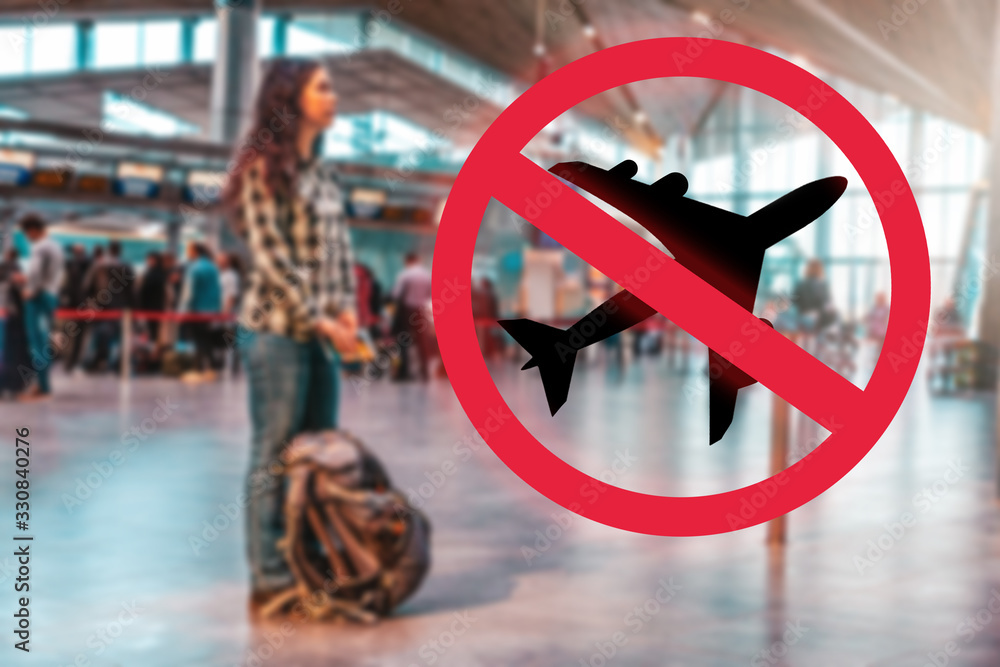 A woman stands with a backpack at the airport, waiting for the departure of the plane.Blurred.Prohibition sign.The concept of a ban on flights, the closure of state borders and the virus pandemic A woman stands with a backpack at the airport, waiting for the departure of the plane.Blurred.Prohibition sign.The concept of a ban on flights, the closure of state borders and the virus pandemic