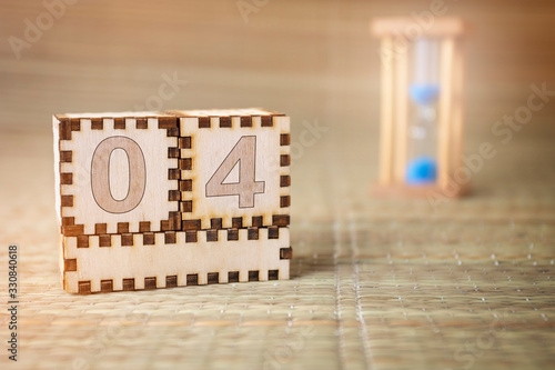 Calendar, wooden cube with date 4 and an empty space for the month, on an abstract woven hourglass background.