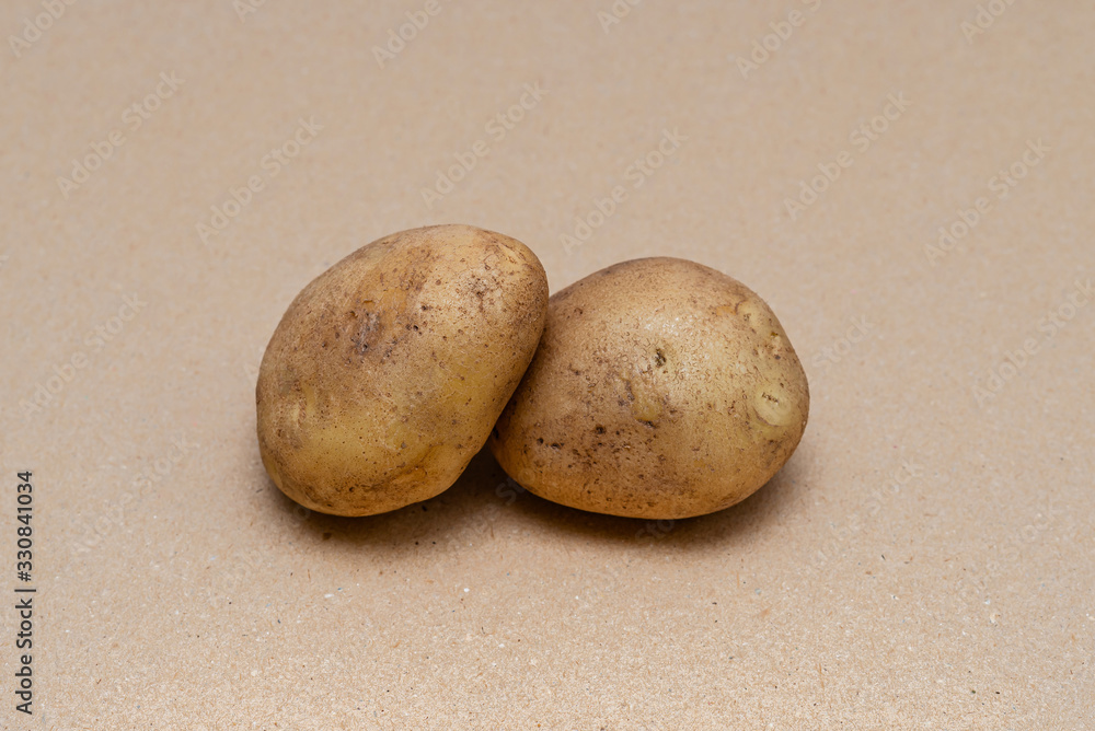 Fototapeta premium raw dirty potatoes on a craft color background
