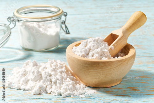 Foto Wooden bowl with corn starch close-up  on a wooden table.