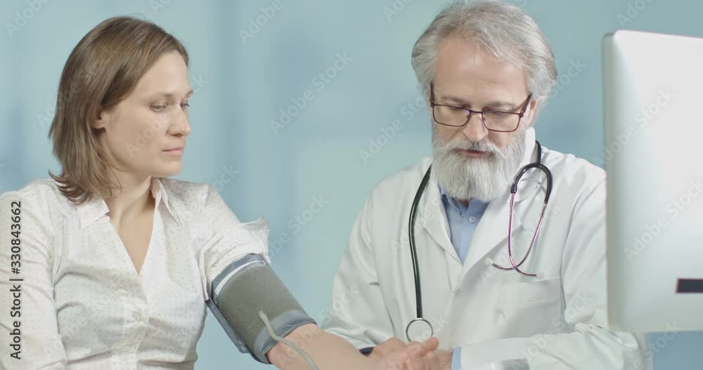 Doctor discussing illnes with his female patient, while measuring her blood pressure Doctor discussing illnes with his female patient, while measuring her blood pressure