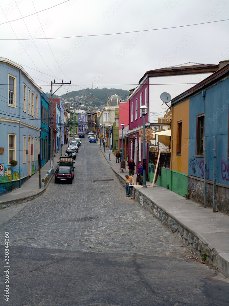 Colorful cobbled street in the city of Valparaiso, Chile, with a hill in the background