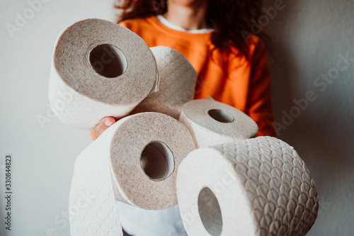 .Young woman hoarding a lot of toilet paper at home. Madness caused by the coronavirus health crisis. photo