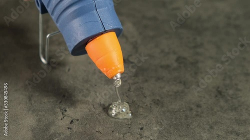 Glue gun drips onto the table. Close up.