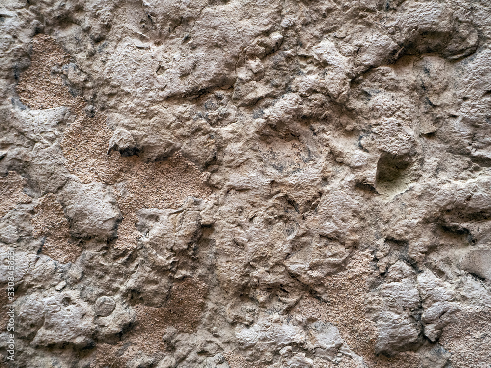 Old crumbling stone. The rough surface of the stone is dented. Vintage stone background.