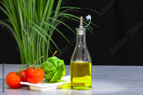 Bottle of olive oil with tomatoes and lettuce photo