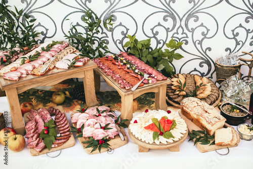 Party meat catering table. Wedding decorative ham slices. Various meat snacks background. Salami slice, sausage piece and fatty lard in ceramic jar. Tasty food background.