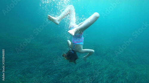 Beautiful girl swimming under the ocean's surface with air bubbles and sunlight, active healthy fitness lifestyle. 