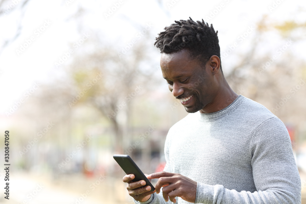 Happy black man using smart phone in a park Happy black man using smart phone in a park