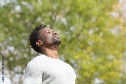 Black serious man breathing fresh air in a park