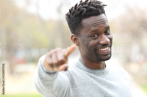 Happy black man pointing at camera in a park