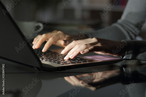 Woman hands typing on laptop at night at home