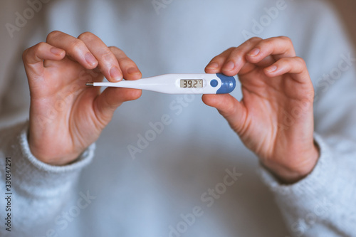Woman holding thermometer with high temperature closeup. Illness concept.