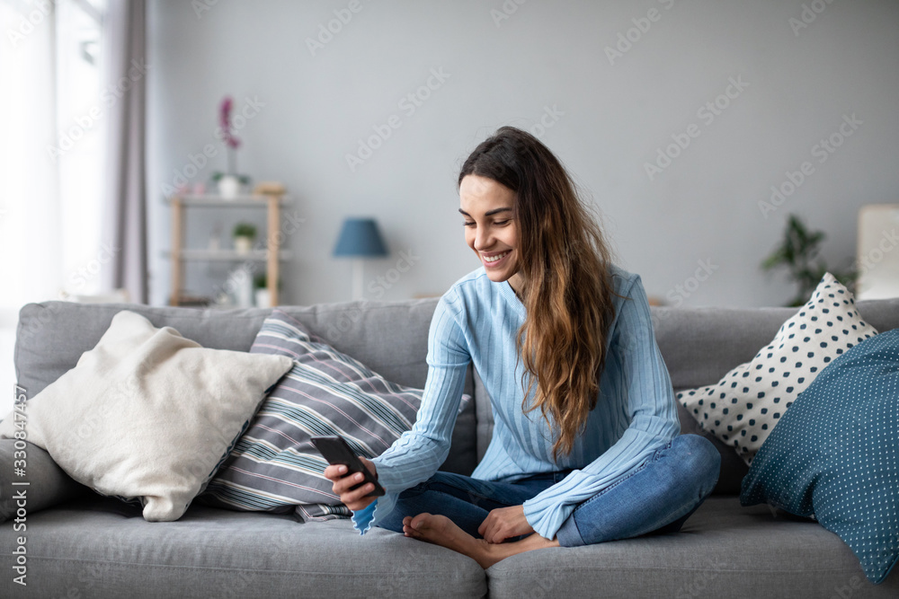 Smiling young woman at home using modern smartphone. Smiling young woman at home using modern smartphone.