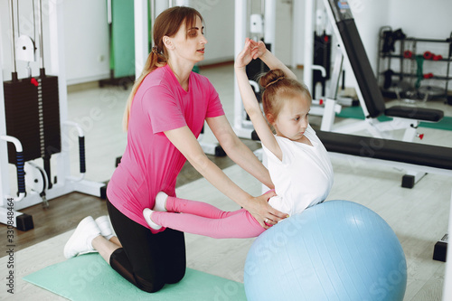 Mother with daughter in a gym. Little girl are engaged in gymnastics