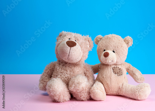 two teddy beige bears sitting huddled together