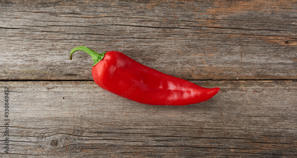 whole red pepper on a gray wooden board