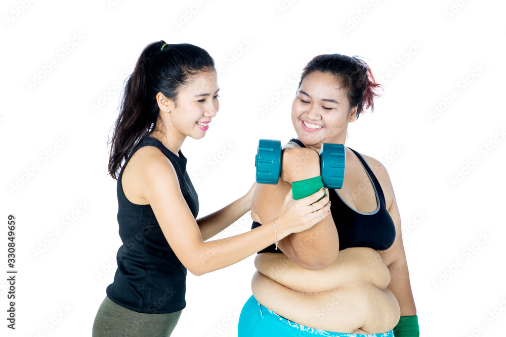 Overweight woman exercising with personal trainer