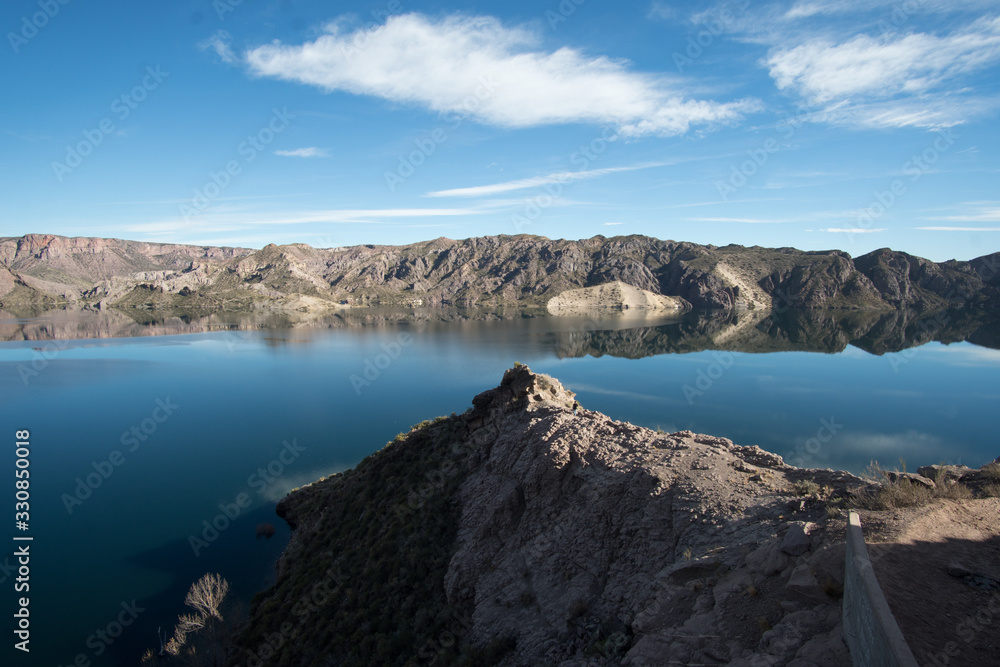 lake surrounded by a mountainous and rocky area that reflects the sky in the middle of the day