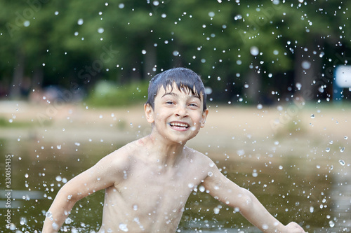 Boy splashes in lake flying splashes of water © justoomm