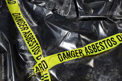 Foto Asbestos warning tape over a pile of affected asbestos product