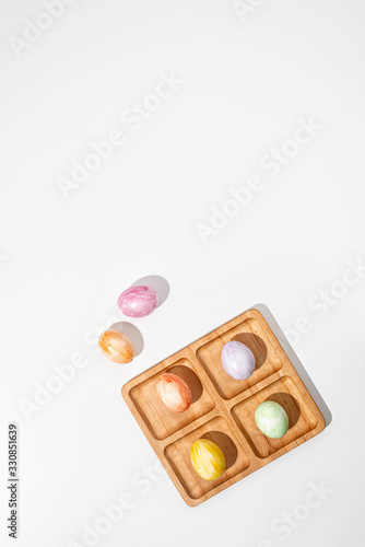 Easter holidays concept.Colorful Easter eggs and wooden stand. White background. Top view.