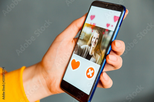 Online dating app in smartphone. Person swiping and liking profiles on relationship site or application. Single guy searching for love partner.
