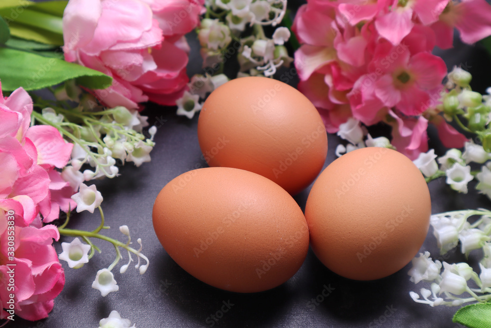 Easter eggs among spring flowers on a black textured background. Easter eggs among spring flowers on a black textured background.