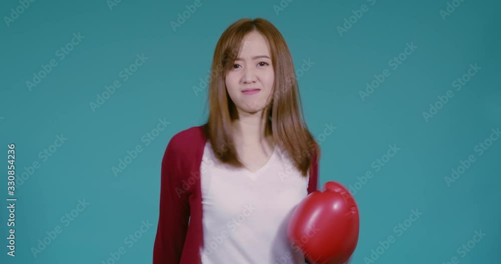Fighting asian woman with boxing gloves punching forward business fight or coronavirus defense on blue background isolated studio shot. Fighting asian woman with boxing gloves punching forward business fight or coronavirus defense on blue background isolated studio shot.
